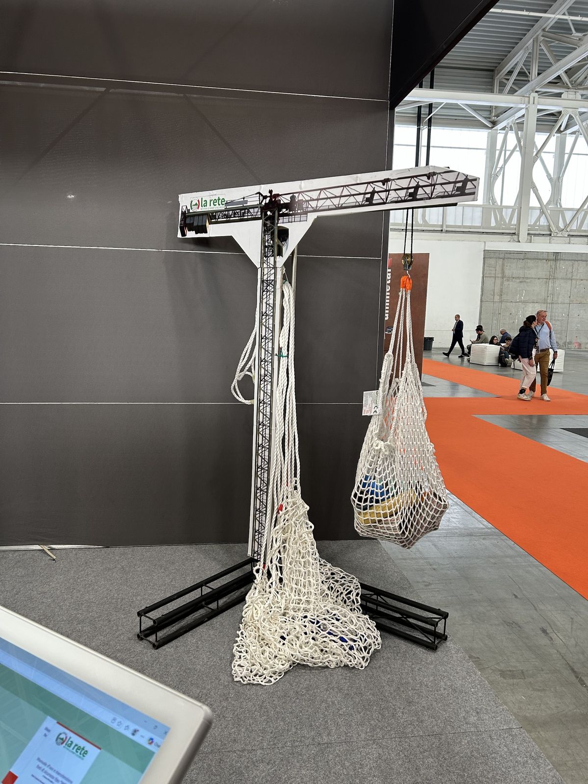 Allo stand de La Rete una gru a torre in miniatura regge le reti di sicurezza